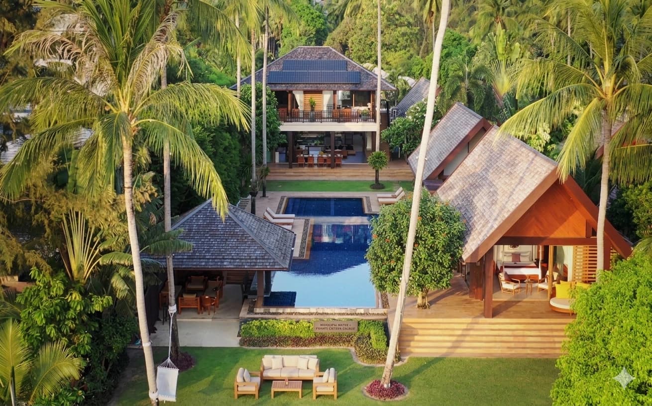 Beachfront villas at Taling Ngam on Koh Samui's west coast, with solar panels on Thai-pitched roofs, a central pool and mature coconut palms.
